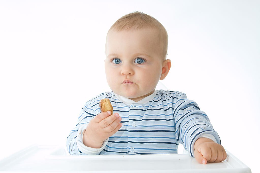 cute baby boy eating biscuits, on white