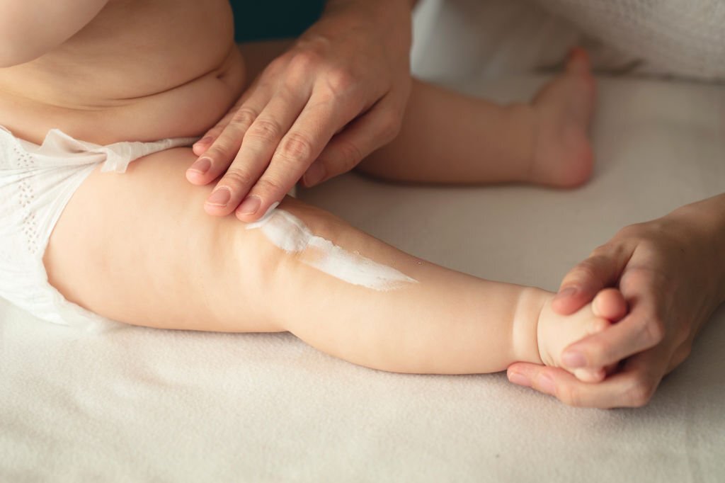 Woman hand holding infant leg. Mother carefully applying medical ointment. Red dry skin allergy from milk formula or other food. Care about baby body. Closeup shot with dslr camera, canon 5dsr