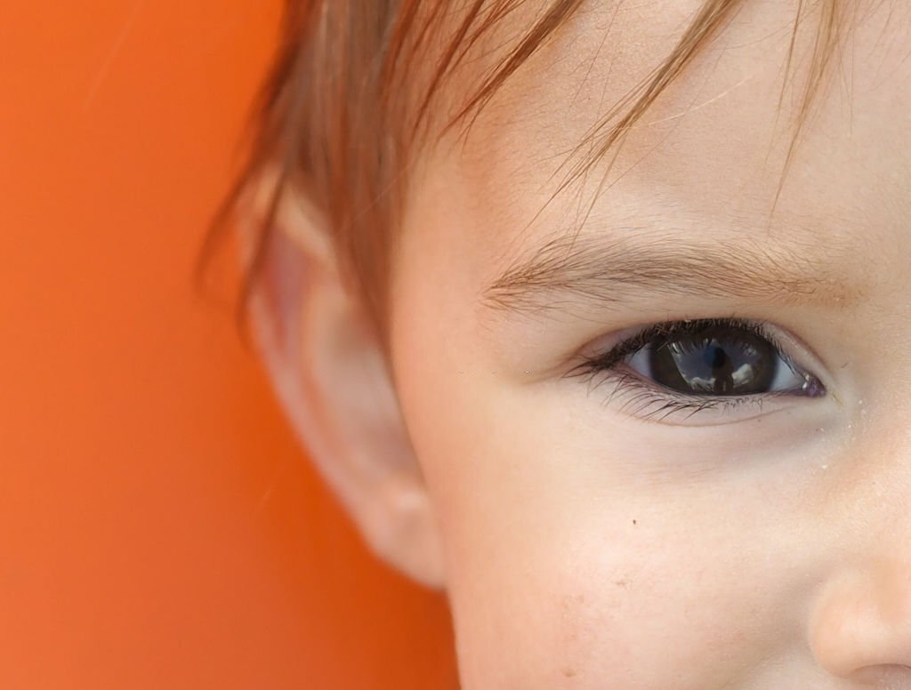 Part of the child's face. Orange background.