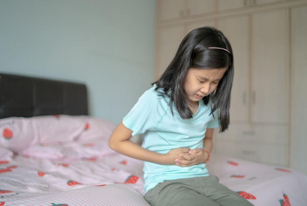 An Asian Chinese girl having a stomach ache at home.
