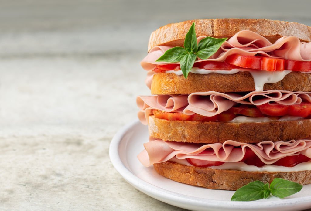Close-up of italian deli sandwich with mortadella, soft cheese Stracchino and tomatoes. Copy space.