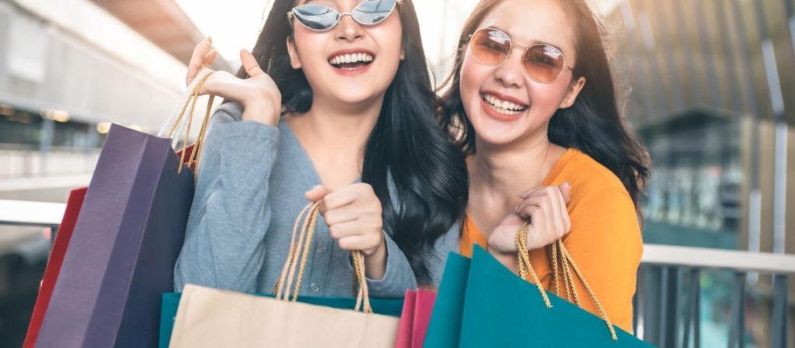 Happy woman with shopping bags enjoying in shopping. Girl holding colour paper bag.Friends walking in shopping mall.time shopping coronavirus crisis or covid19 outbreak.