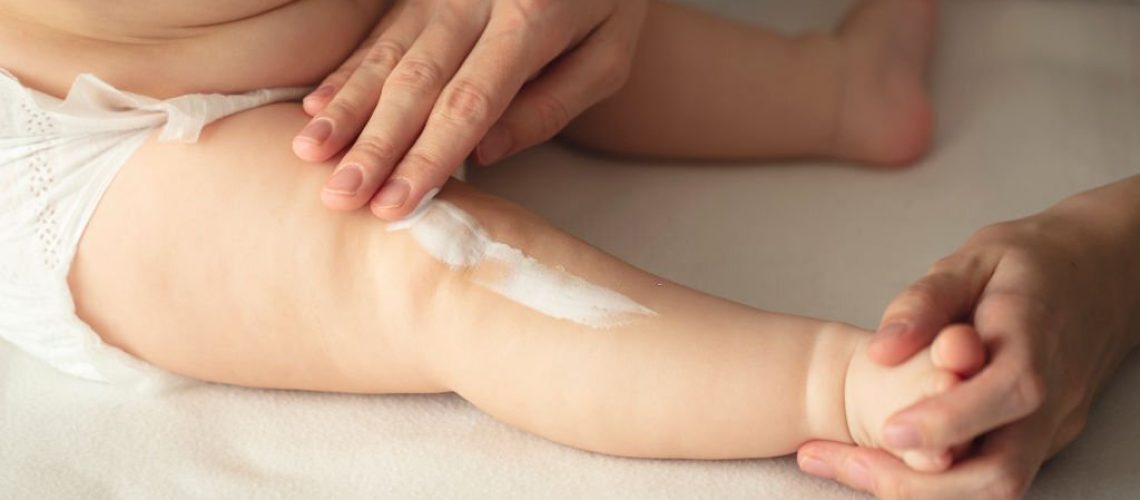 Woman hand holding infant leg. Mother carefully applying medical ointment. Red dry skin allergy from milk formula or other food. Care about baby body. Closeup shot with dslr camera, canon 5dsr