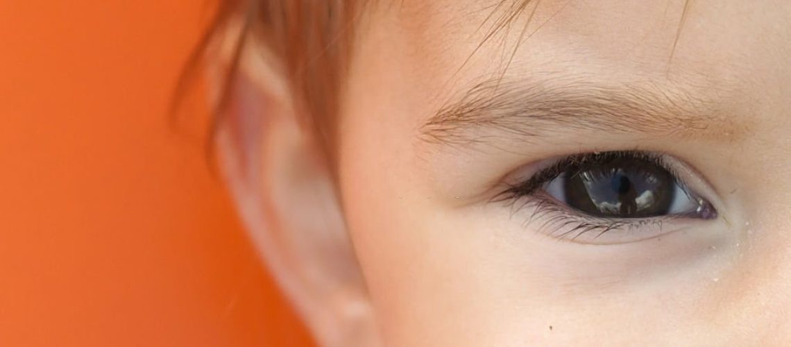 Part of the child's face. Orange background.