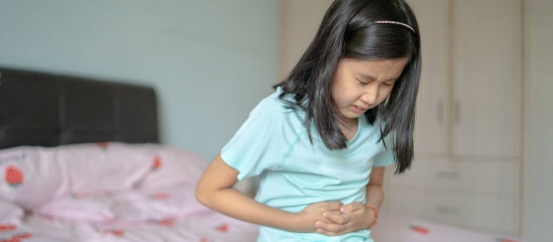 An Asian Chinese girl having a stomach ache at home.