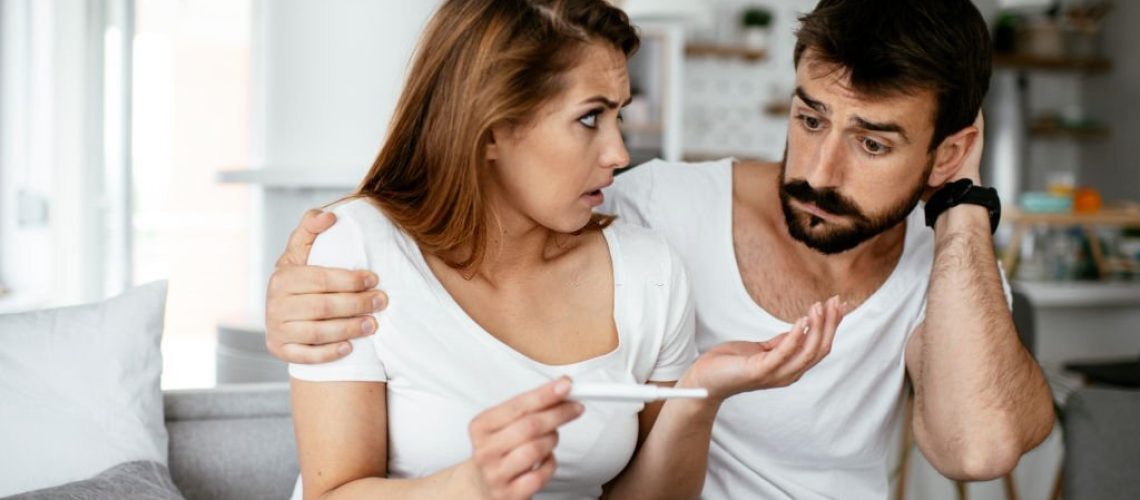 Shocked couple is looking positive pregnancy test stock photo. Shallow DOF. Developed from RAW; retouched with special care and attention; Small amount of grain added for best final impression. 16 bit Adobe RGB color profile.