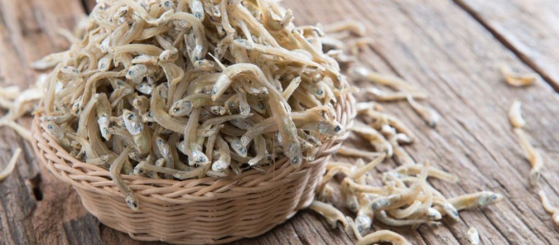 Raw anchovies over rustic wooden background