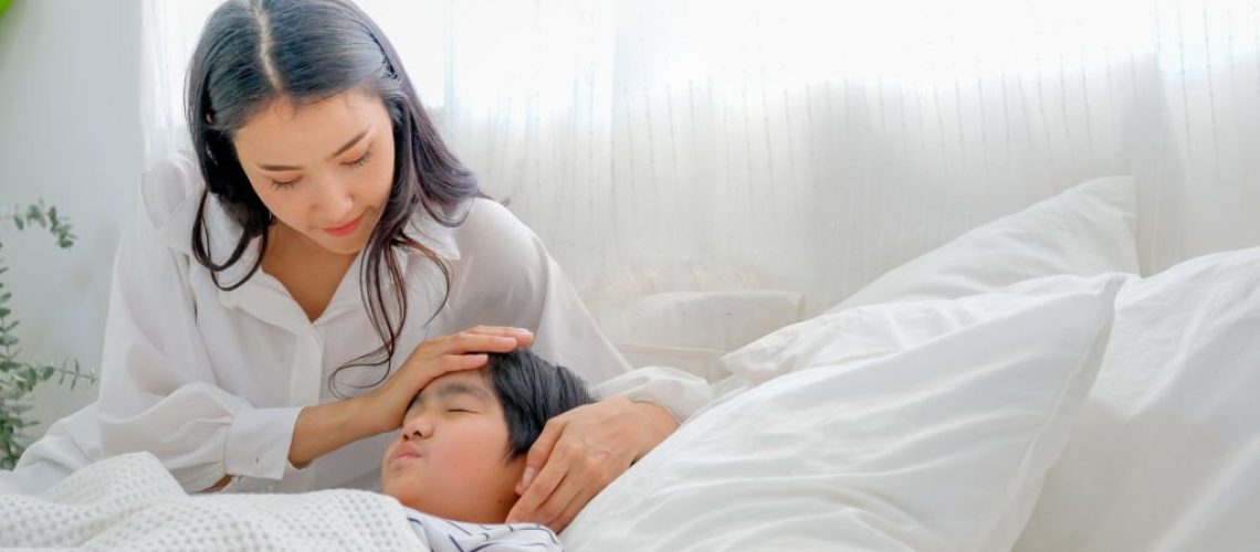 Asian mother take care her son during cold in bedroom with day light.
