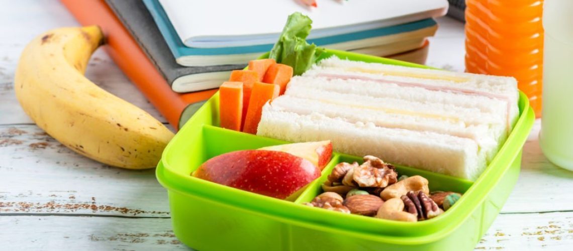 Lunch box set of Ham cheese sandwich with carrot and mixed nuts, apple in box, banana and orange juice with milk. Kid bento pack for school.