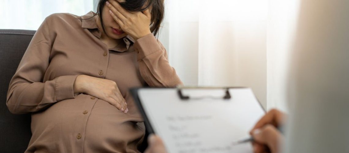 The pregnant mother is discussing depression symptoms during pregnancy with a specialist doctor or psychiatrist. The future mom is unhappy, worried, and stressed. Mental health concept