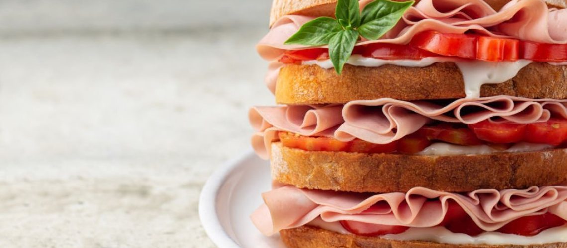 Close-up of italian deli sandwich with mortadella, soft cheese Stracchino and tomatoes. Copy space.